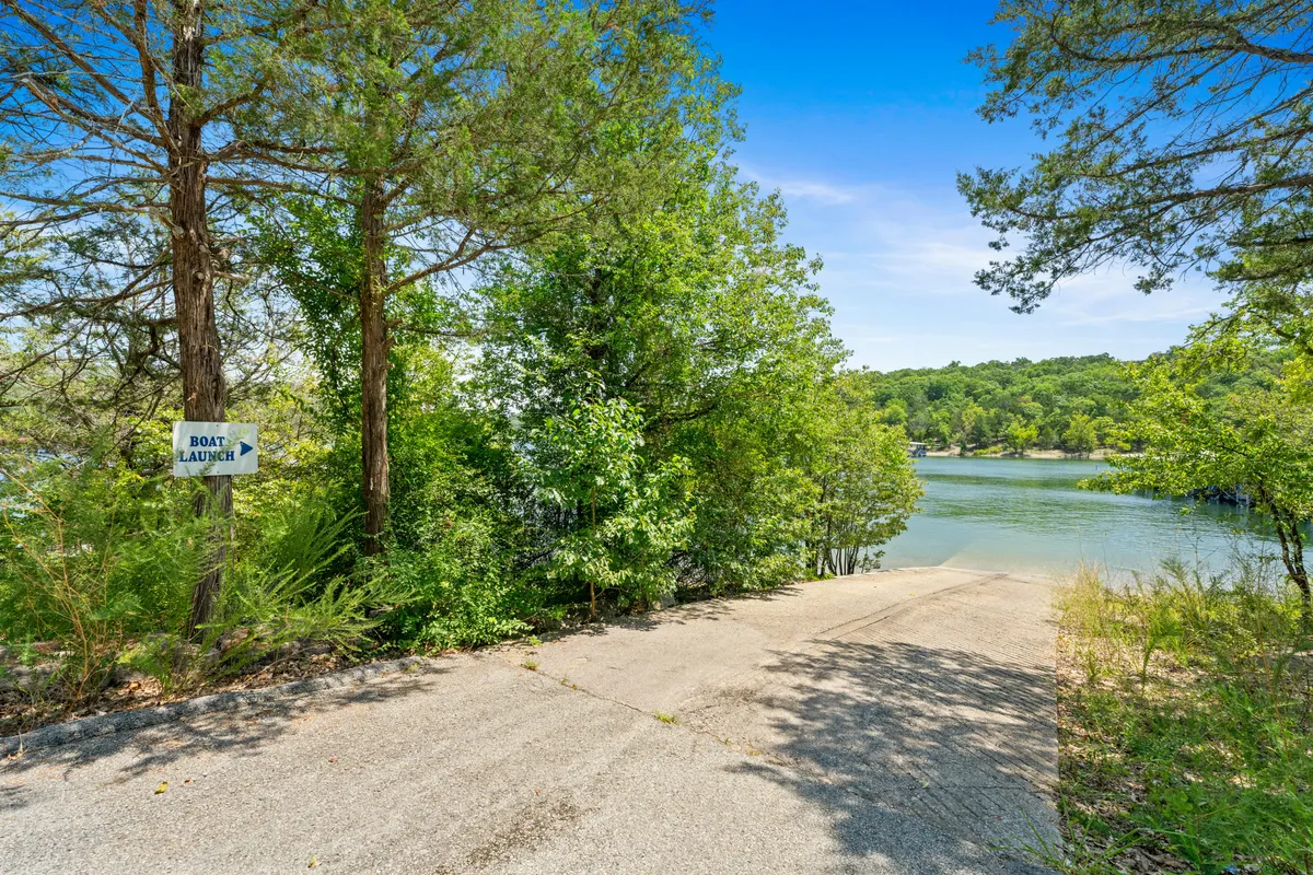 This image shows a clearly marked boat launch ramp sloping gently into the calm waters of Table Rock Lake. The scene is framed by lush greenery on both sides, and the surrounding area suggests a peaceful, easy access point for boating or fishing adventures. The tranquil lake stretches into the distance, inviting exploration and aquatic fun.