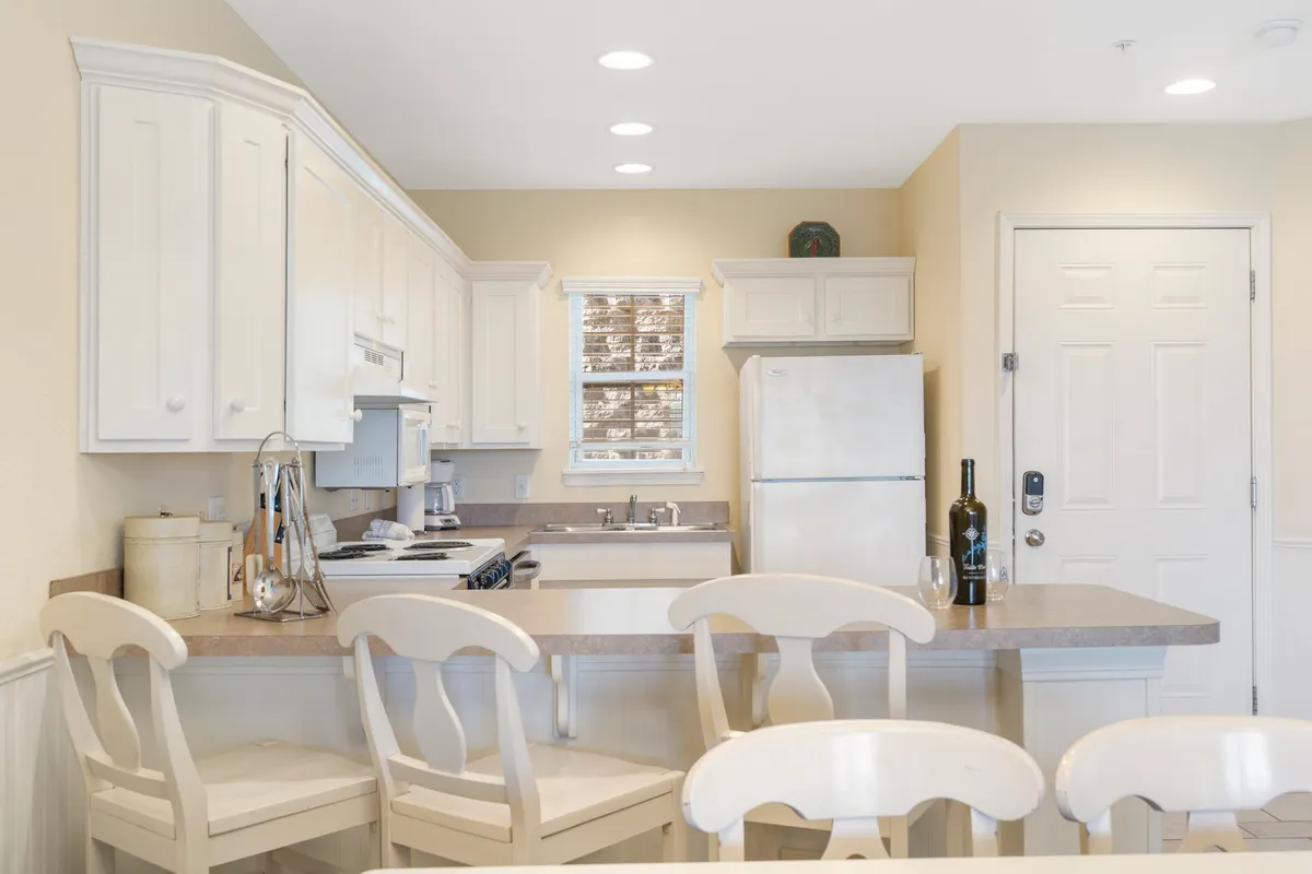 A spacious, modern kitchen featuring a large island with seating, white cabinetry, and stainless steel appliances. The space is bright and inviting, ideal for preparing meals or gathering for conversation while cooking.