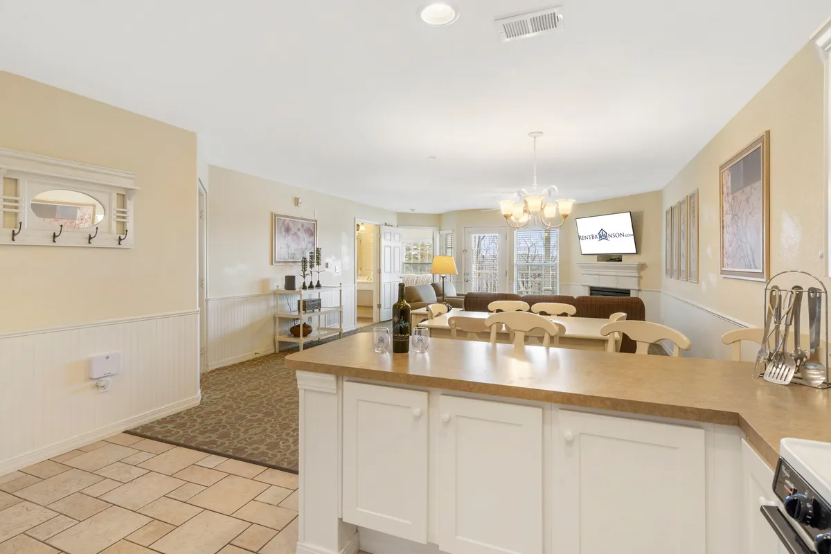 An open-concept space connecting the kitchen island, dining area, and a comfortable seating nook. The area is decorated with cozy touches and artwork, encouraging both cooking and relaxed socializing.