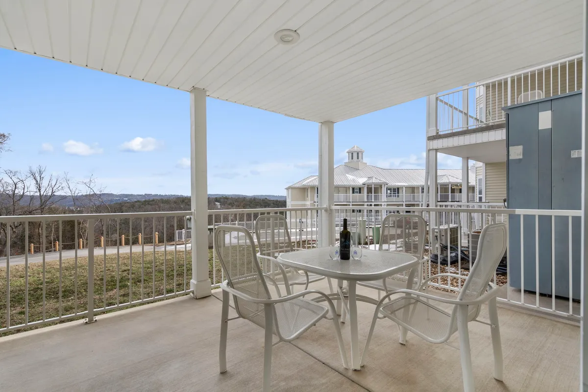A serene exterior deck scene with a table set with a wine bottle and chairs, overlooking a tranquil landscape—perfect for enjoying a quiet drink or meal outdoors.