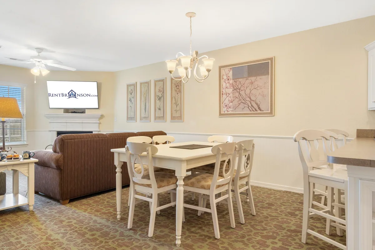 This shot shows a welcoming interior with a dining table at the forefront, a comfortable sofa, chandelier, wall art, and a television. The arrangement is perfect for family meals, game nights, or simply spending quality time, capturing the lively, social atmosphere described in the section.