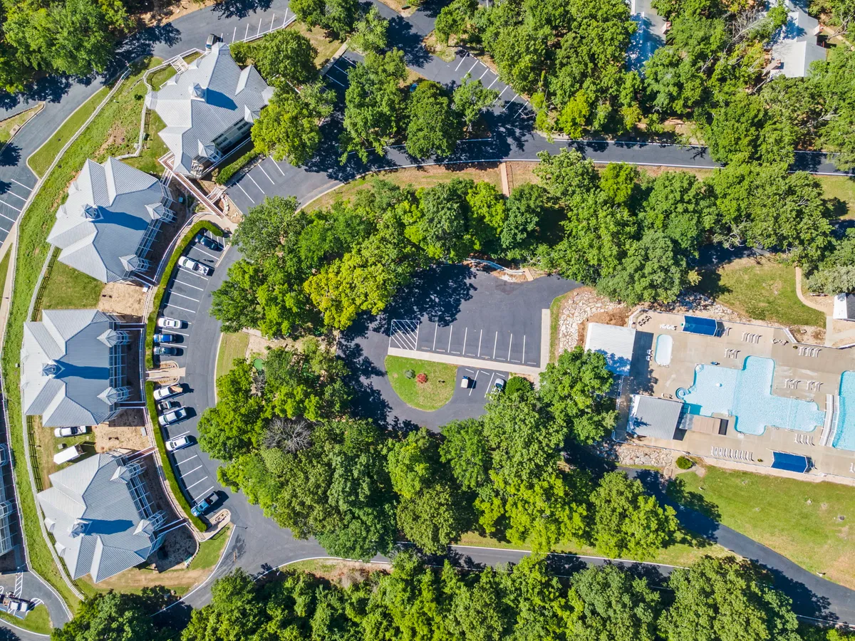 A resort pool surrounded by lush greenery, lounge chairs, and residential buildings in the background. The area feels inviting and leisurely, ideal for relaxation or social time after exploring or trailing with pets.
