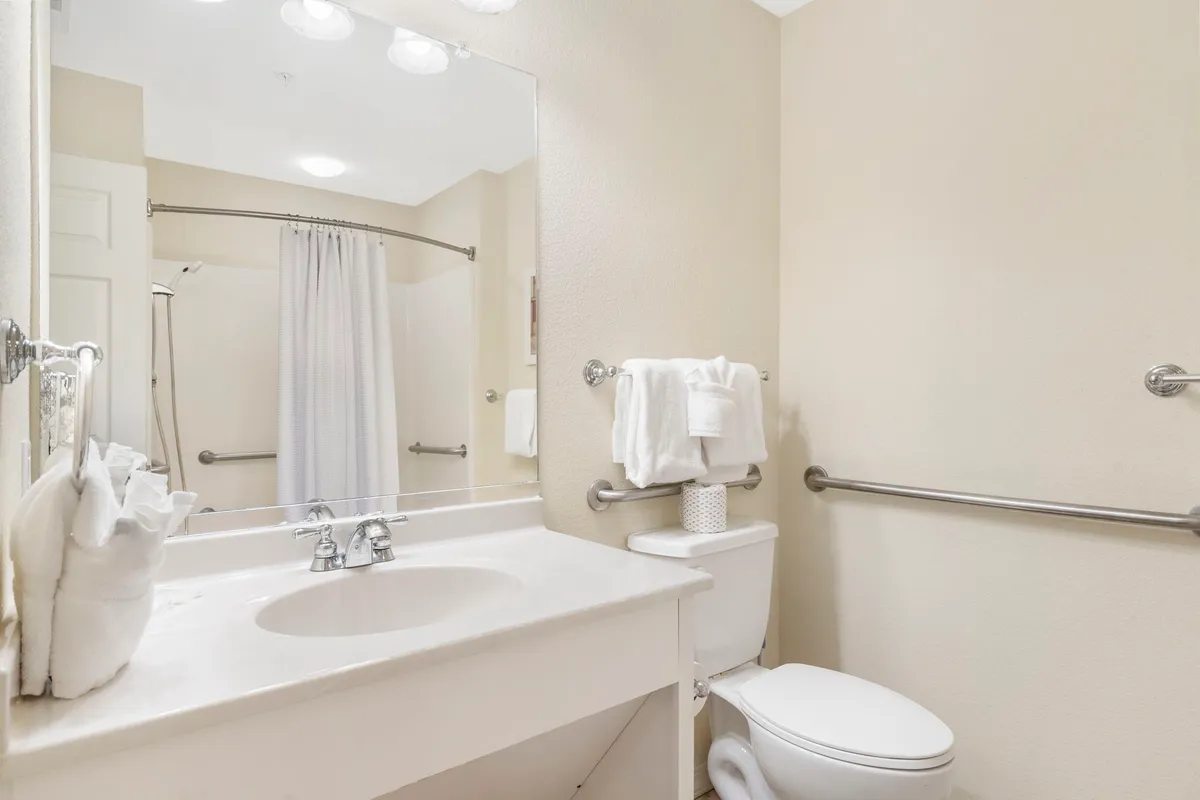 A bright, clean bathroom with a modern sink, large mirror, toilet, and glass-enclosed shower area. The space is organized and tranquil, suggesting a comfortable place to refresh after outdoor adventures.